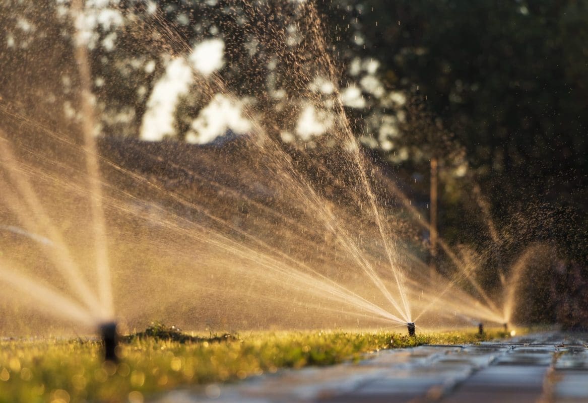 automatic sprinkler system watering lawn sunset scaled e1687342531632