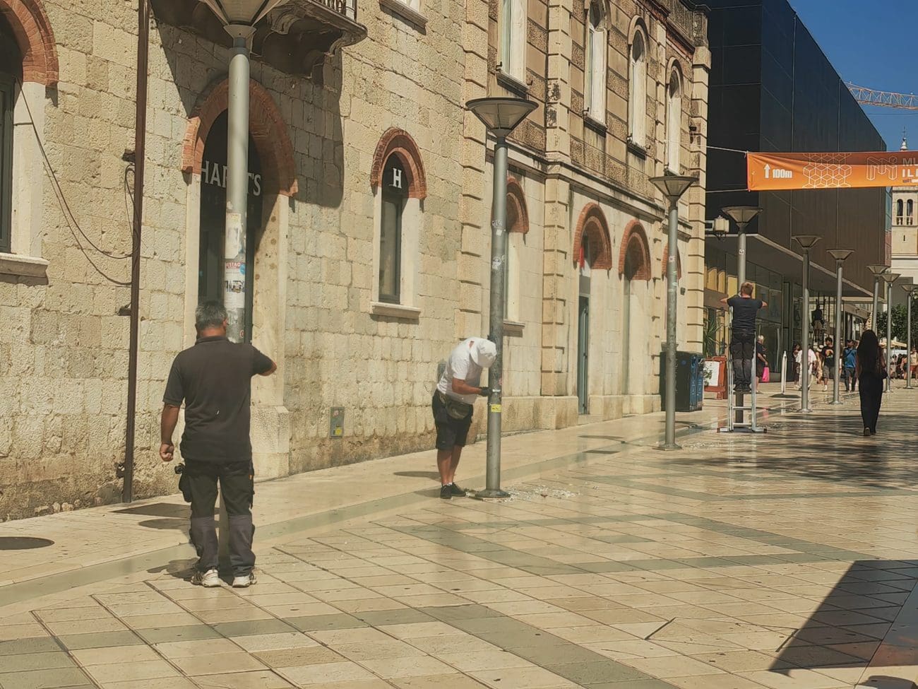 FOTOGALERIJA Radnici na vrućini u centru Splita skidaju naljepnice s rasvjetnih stupova